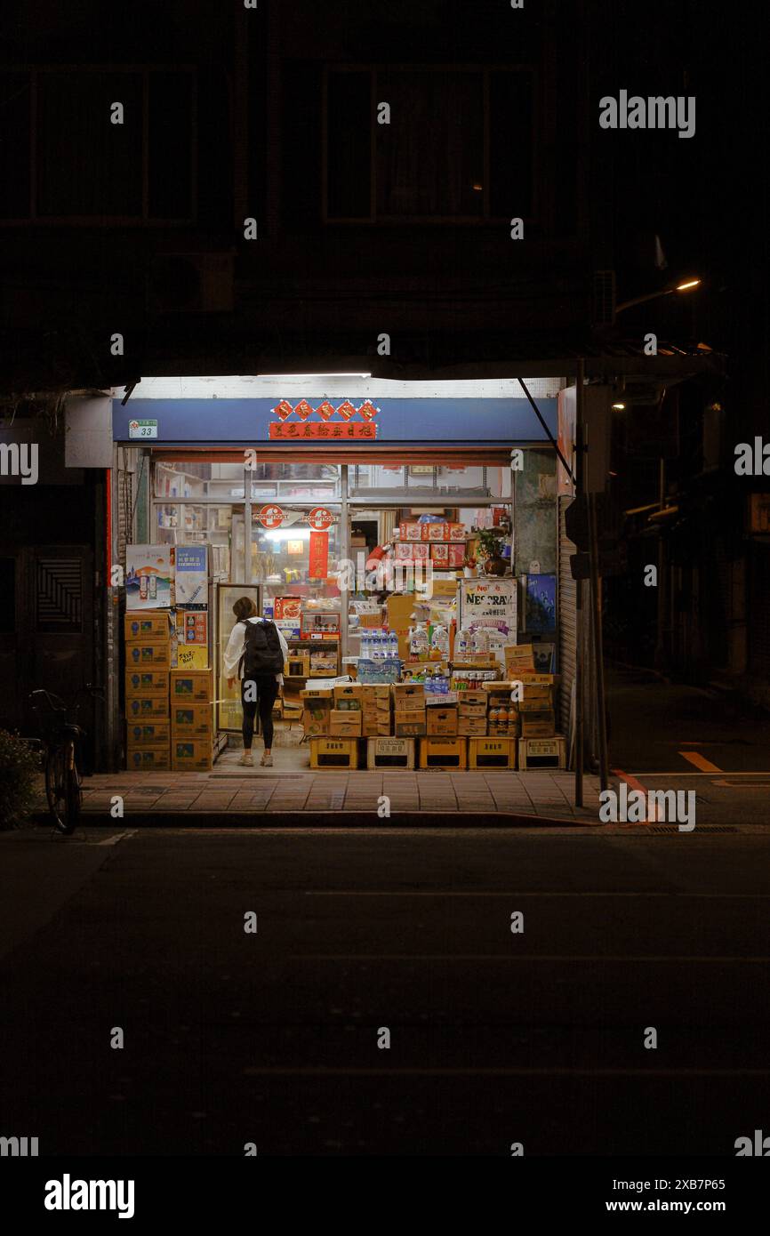 Une femme debout devant une librairie la nuit Banque D'Images