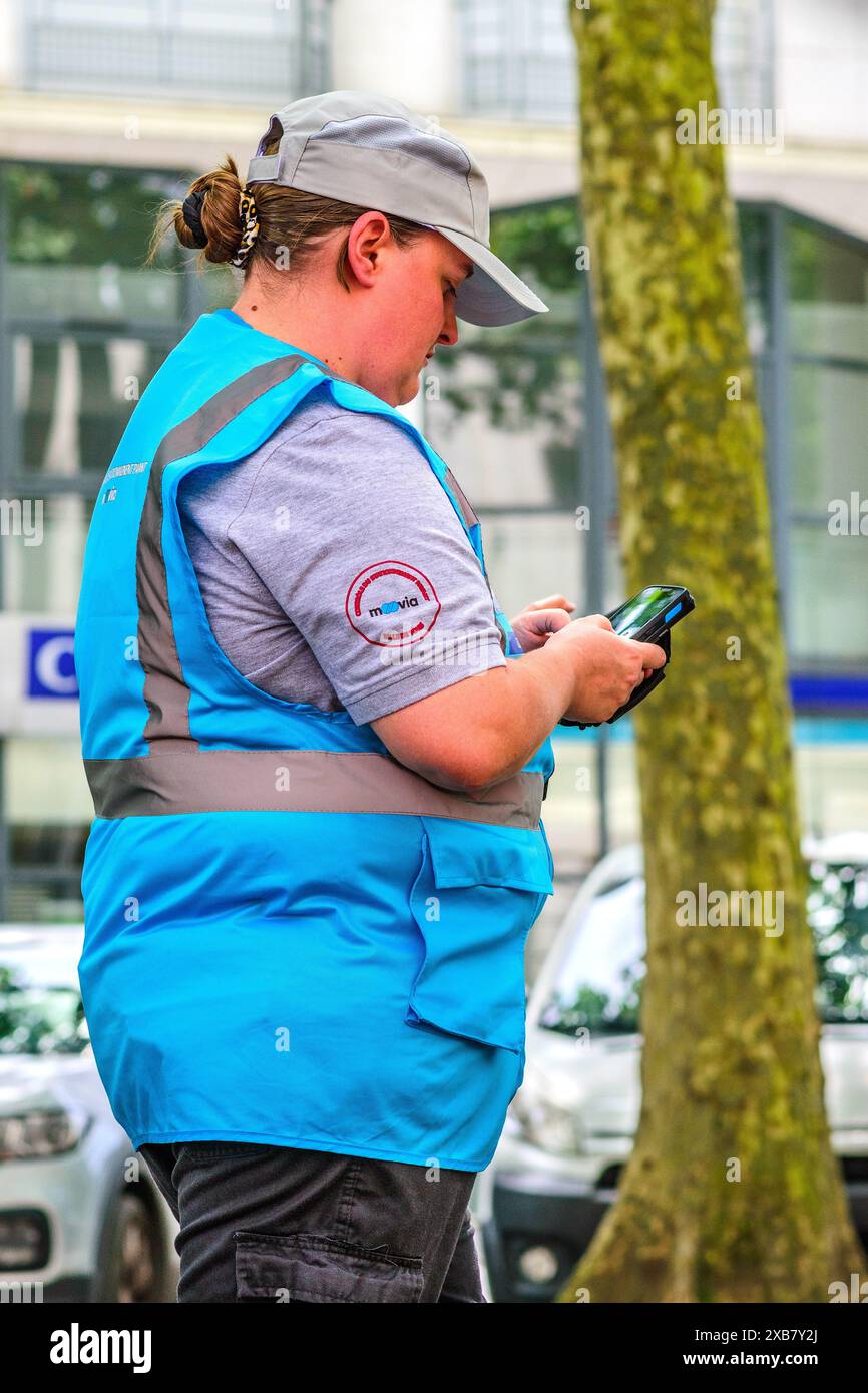 Gardienne de la circulation féminine avec l'uniforme de la société Moovia cheaking voiture date sur smartphone - Tours, Indre-et-Loire (37), France. Banque D'Images