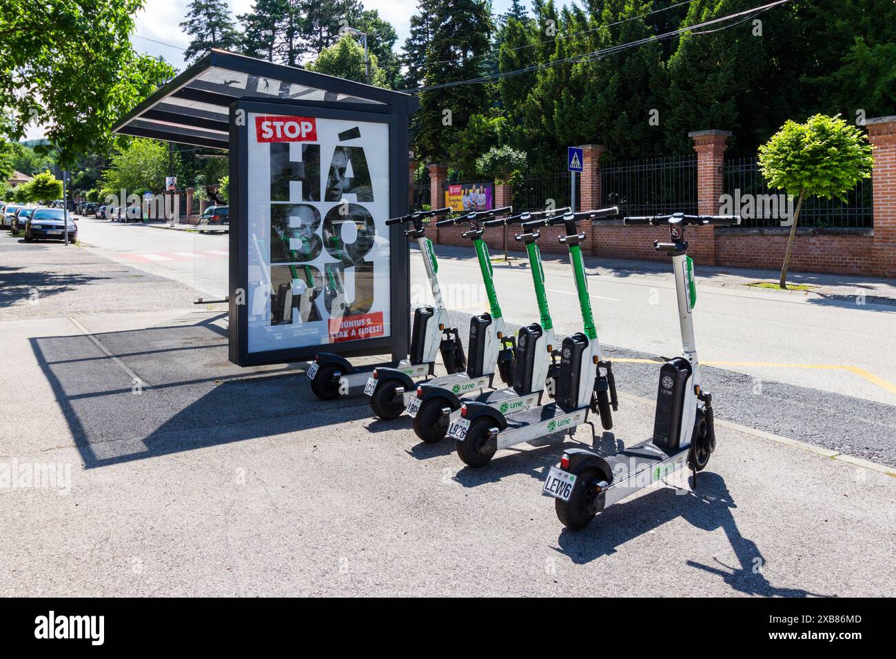 Les scooters électriques chaux alignés à côté de l'arrêt de bus avec la publicité du gouvernement hongrois "Stop War", Sopron, Hongrie Banque D'Images