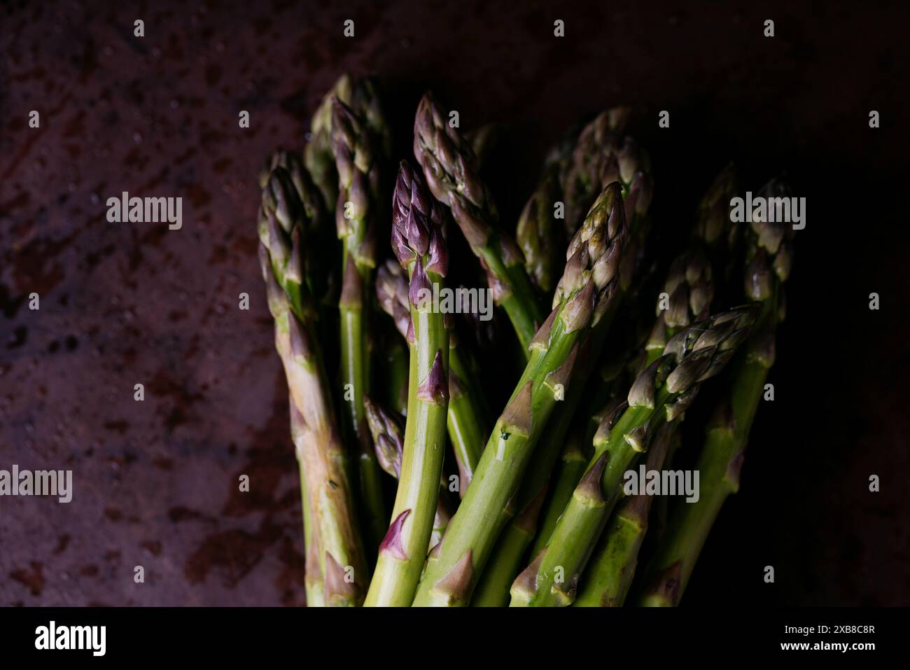 Gros plan de lances d'asperges vertes fraîches regroupées. Les pointes des asperges sont fermes et légèrement violettes. L'asperge est présentée agains Banque D'Images