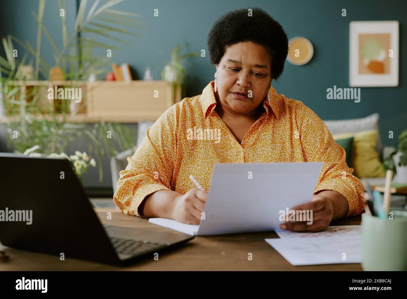 Femme afro-américaine assise à table et travaillant avec des docs avec concentration sur son visage Banque D'Images