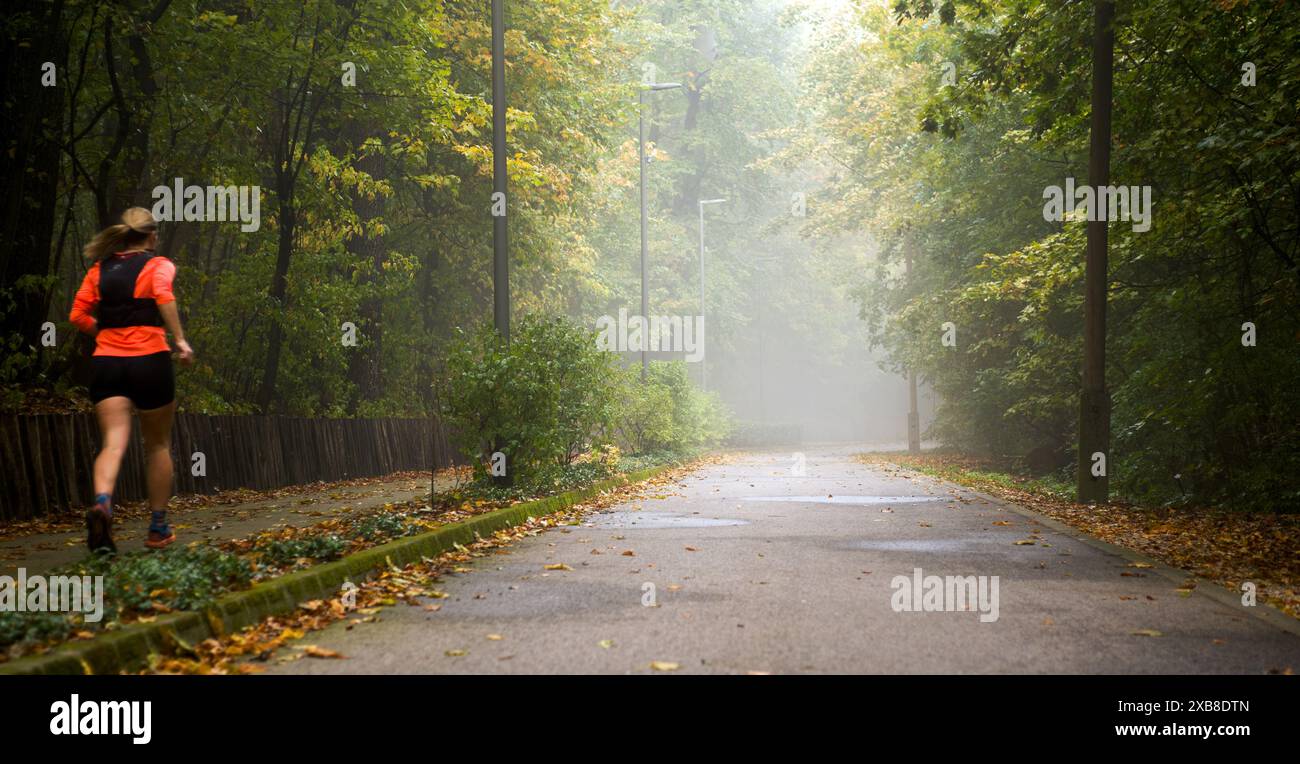 Ruelle de parc brumeuse, femme qui court Banque D'Images