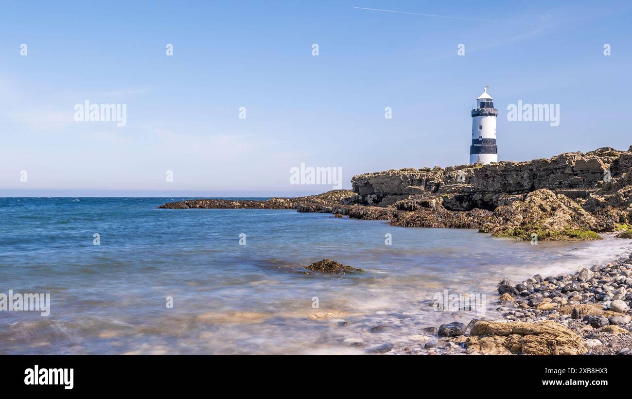 Phare sur le bord d'un promontoire rocheux. Le phare est situé à Penmon point, Angelsey, au nord du pays de Galles. La journée est ensoleillée Banque D'Images