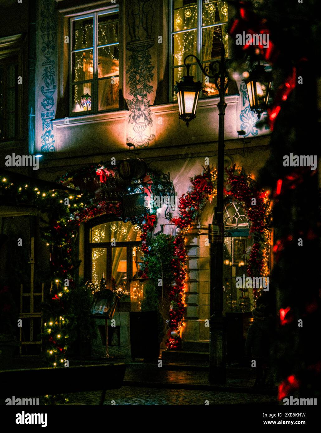 Une scène de rue festive avec des fenêtres éclairées dans un grand bâtiment pendant Noël Banque D'Images