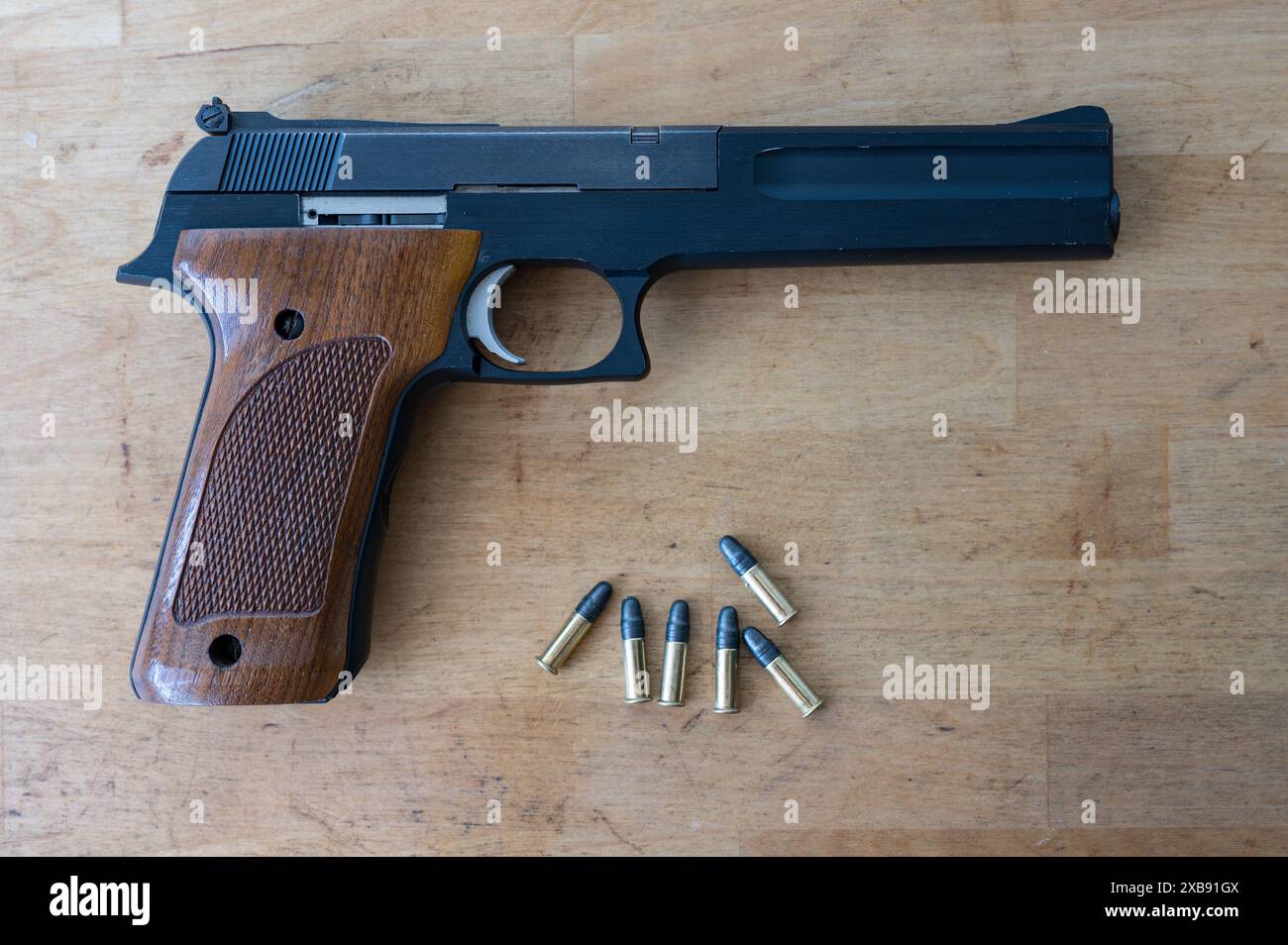 Un joli pistolet classique de calibre .22 et quelques balles standard sur la table en bois Banque D'Images