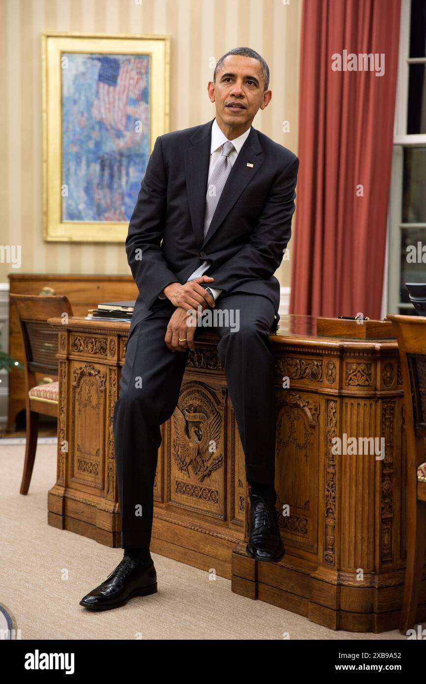 Le Président des États-Unis Barack Obama est assis au bord du Resolute Desk lors d'une réunion au Bureau ovale le 19 décembre 2012 Banque D'Images