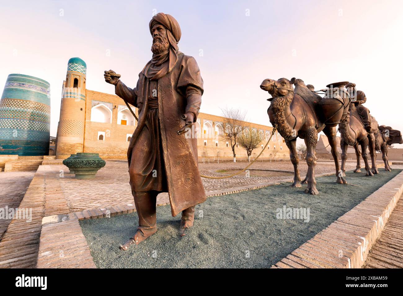 Khiva, Ouzbékistan - mars -29- 2024 : groupe de sculpture d'une ancienne caravane avec des chameaux transportant diverses marchandises le long de la route de la soie et deux hommes en tradi Banque D'Images