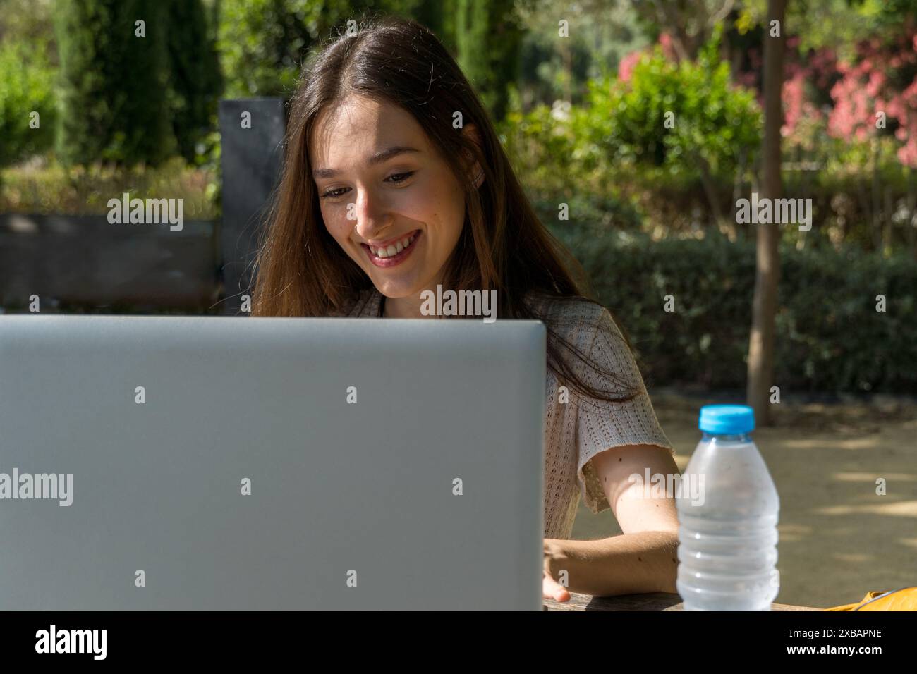 Étudiante souriante et interagissant avec son ordinateur portable sur le campus. Vie étudiante, technologie, éducation, début des classes. Banque D'Images