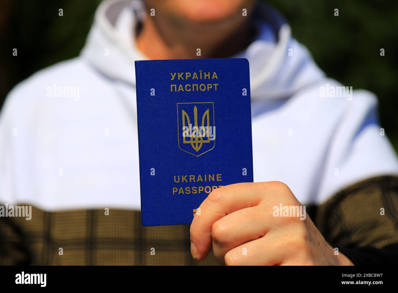 Un homme tient dans ses mains un passeport ukrainien avec une inscription en ukrainien - passeport de l'Ukraine. Concept de voyage, réfugié, touriste, émigrant, mobi Banque D'Images