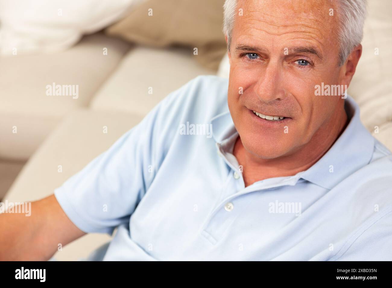 Heureux et en bonne santé homme âgé ou d'âge moyen assis sur un canapé à la maison souriant et heureux Banque D'Images