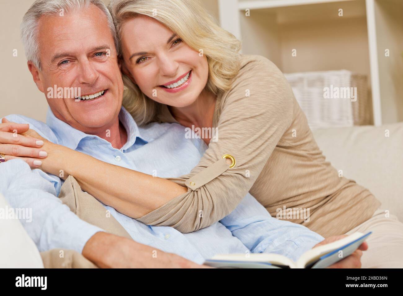 Attrayant couple de femmes âgées en bonne santé à la maison souriant lisant un livre Banque D'Images