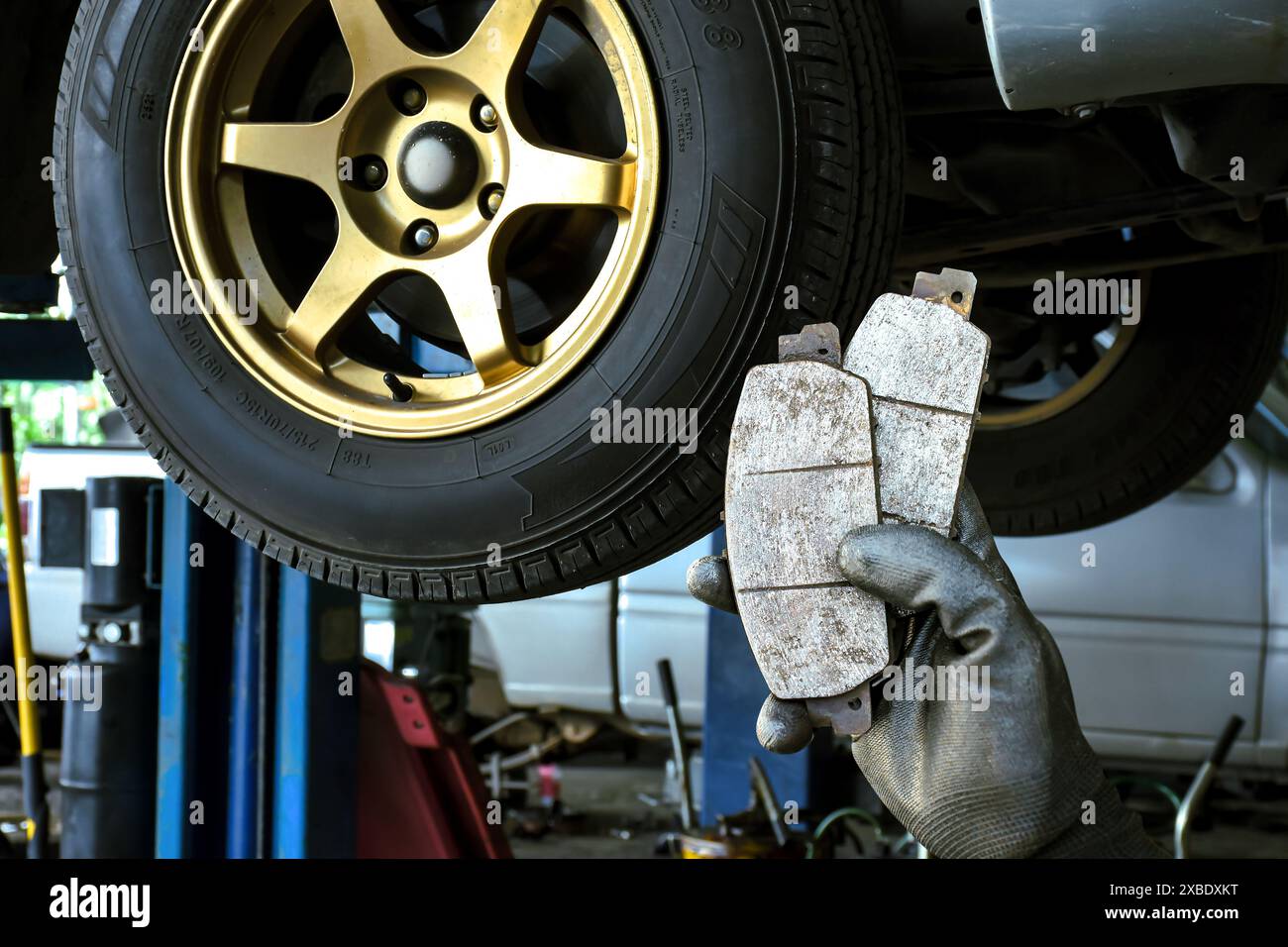 Concept d'entretien du système de freinage de voiture , main de mécanicien tenant une plaquette de frein de voiture dans le garage de réparation de voiture Banque D'Images