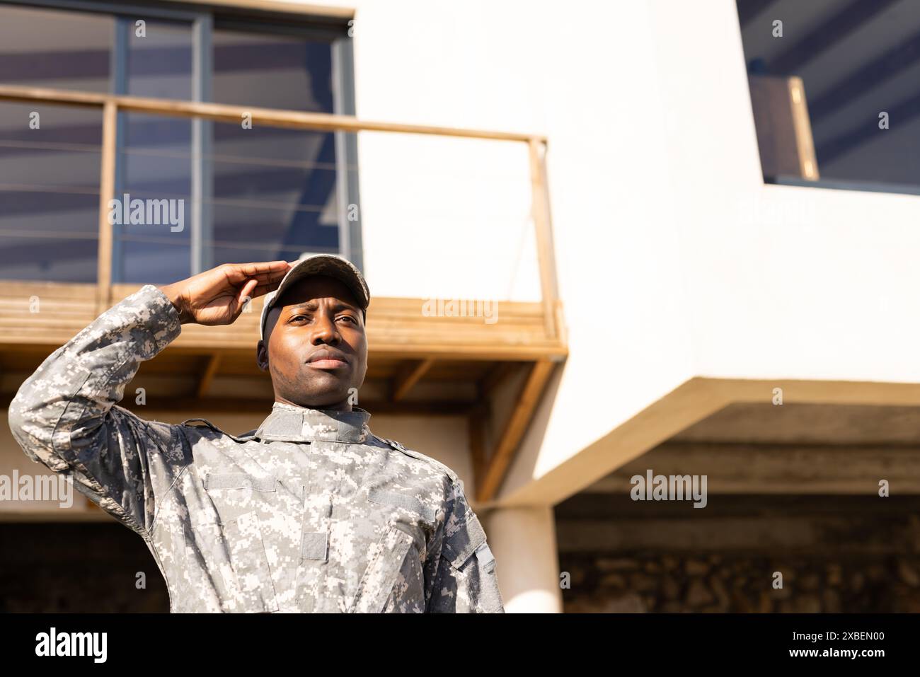 Jeune soldat afro-américain en uniforme militaire saluant à l'extérieur du bâtiment moderne Banque D'Images Jeune soldat afro-américain en uniforme militaire saluant à l'extérieur du bâtiment moderne Banque D'Images