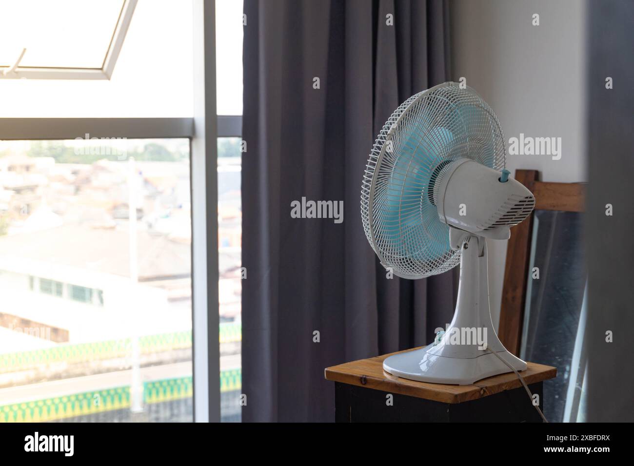 concept de concept de vague de chaleur en été, face au ventilateur de bureau dans une fenêtre pour une meilleure circulation de l'air dans la paternité de l'appartement et la parentalité, bébé h. Banque D'Images