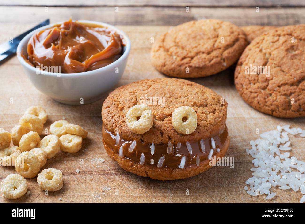 Biscuits avec de la pâte de crème en forme de monstres pour la célébration d'Halloween. Des visages faits maison amusants faits de biscuits à l'avoine et de lait condensé bouilli Banque D'Images Biscuits avec de la pâte de crème en forme de monstres pour la célébration d'Halloween. Des visages faits maison amusants faits de biscuits à l'avoine et de lait condensé bouilli Banque D'Images