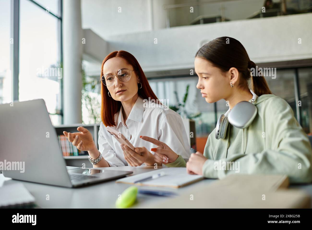 Une femme rousse enseigne à une adolescente, tutorat après les leçons scolaires ensemble à l'aide d'un ordinateur portable. Banque D'Images