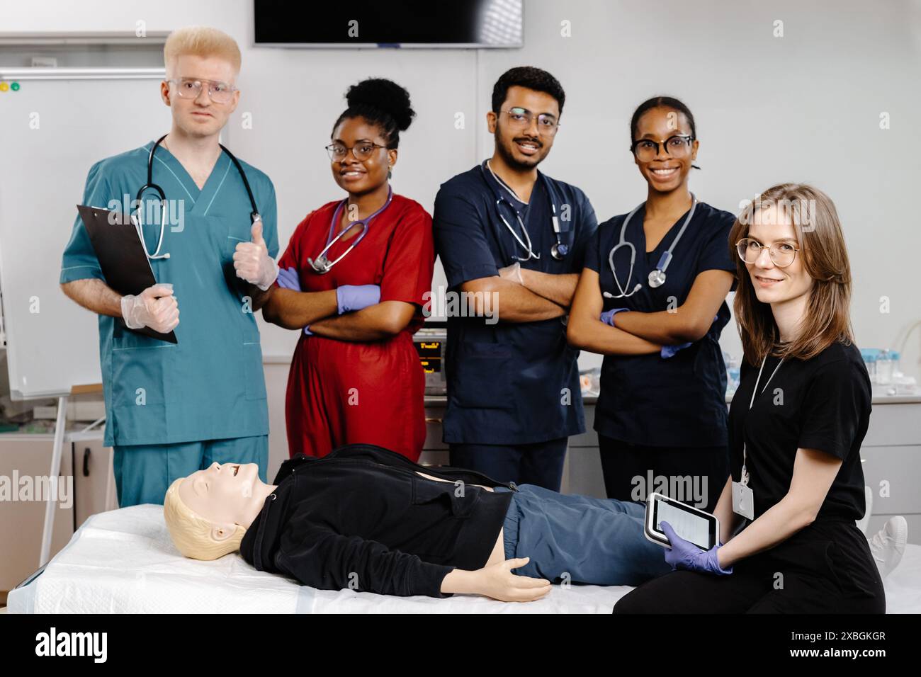 Un groupe d'étudiants en médecine en gommage pratiquent la RCR sur un mannequin de formation au cours d'une séance de formation médicale. Banque D'Images