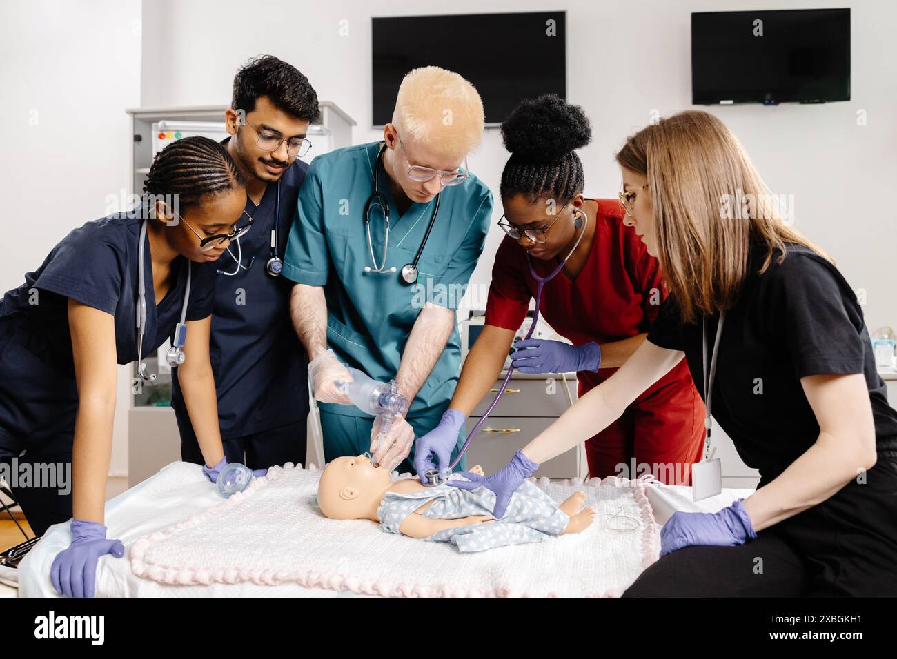 Les étudiants en médecine en gommage pratiquent la RCR sur un mannequin bébé lors d'une séance de formation. Banque D'Images