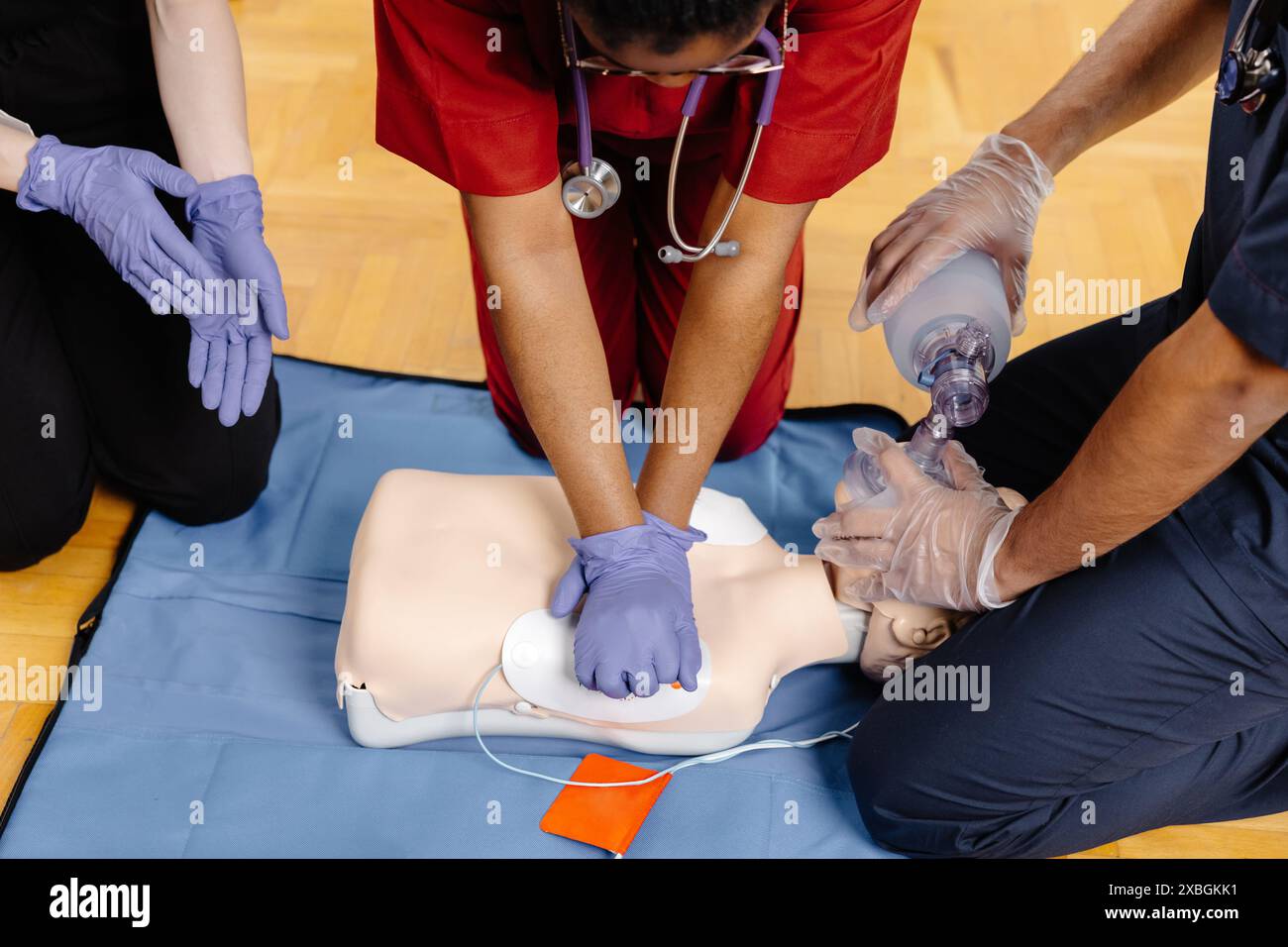 Trois personnes pratiquent la RCP sur un mannequin de formation. Une personne effectue des compressions thoraciques tandis qu'une autre utilise un masque à valve de poche pour administrer b. Banque D'Images