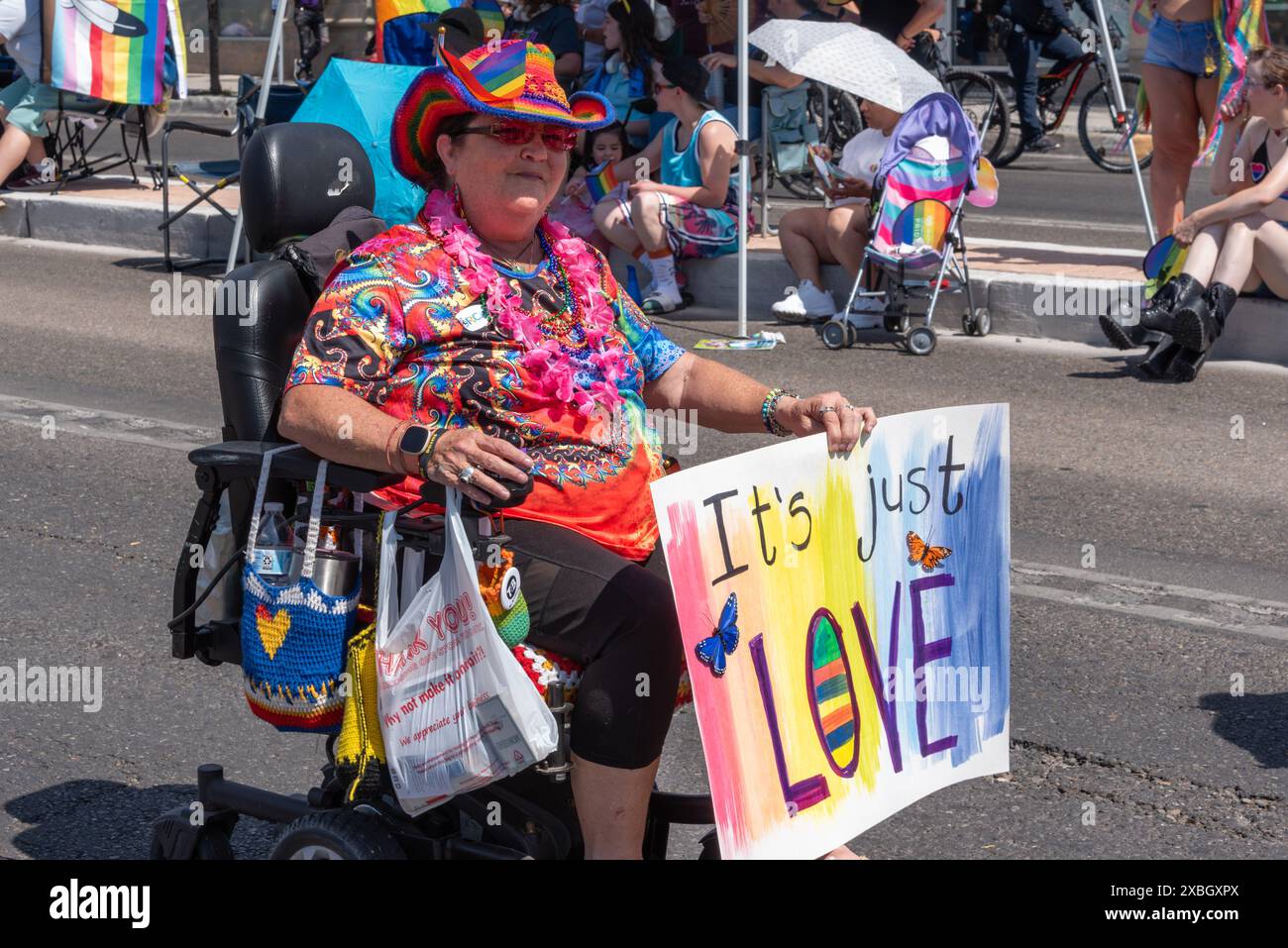 Femme en fauteuil roulant motorisé dans la Albuquerque Pride Parade 2024 tient un panneau qui dit que je n'aime pas juste, Albuquerque, Nouveau Mexique, USA. Banque D'Images