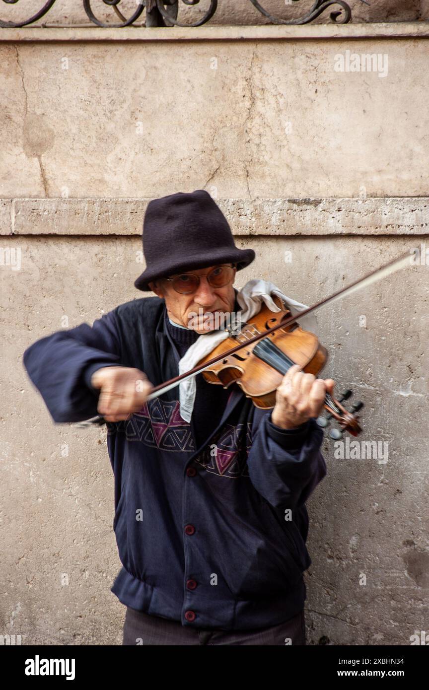 Un artiste de rue solitaire joue de son violon pour les touristes de passage espérant gagner de l'argent à Rome, en Italie Banque D'Images