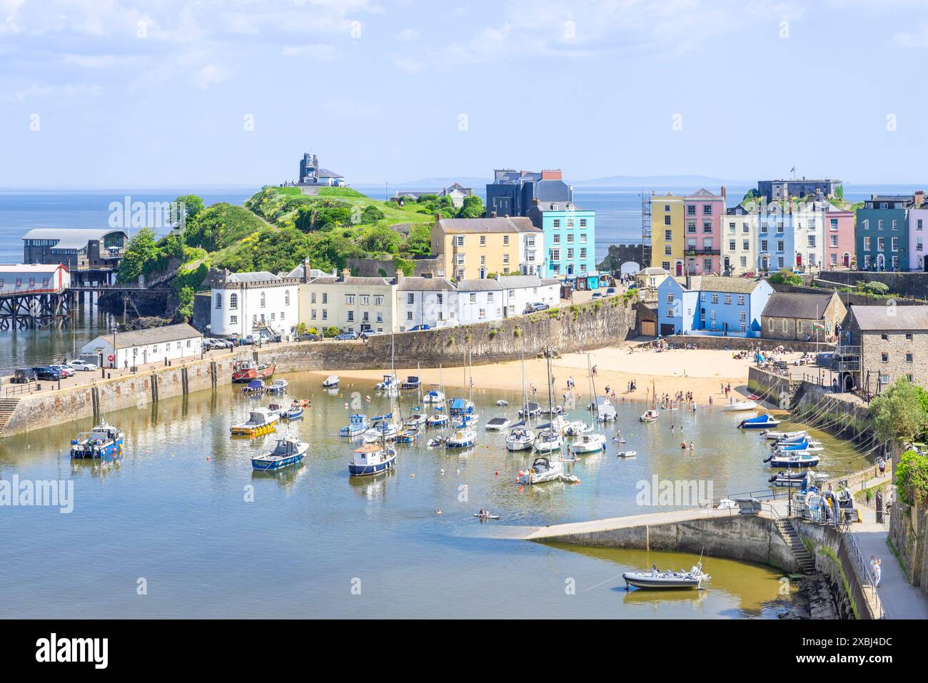 Petits bateaux dans le port de Tenby et la plage du port de Tenby à marée haute avec les maisons colorées de Tenby baie de Tenby Carmarthan Pembrokeshire West Wales UK GB Banque D'Images