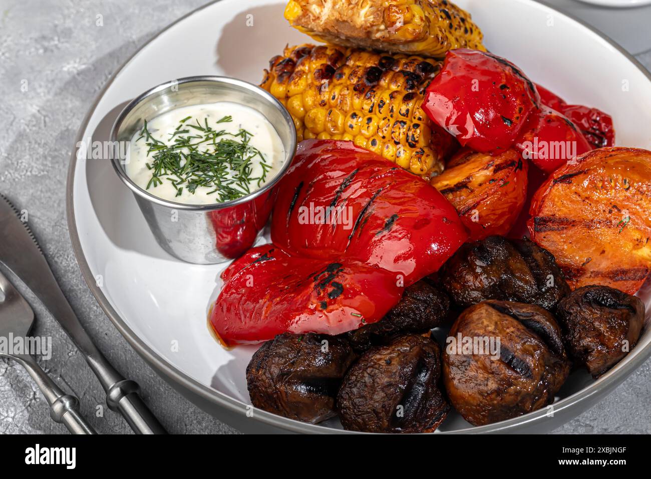 Légumes grillés sur une assiette, maïs et poivrons, champignons et sauce. Copier l'espace Banque D'Images
