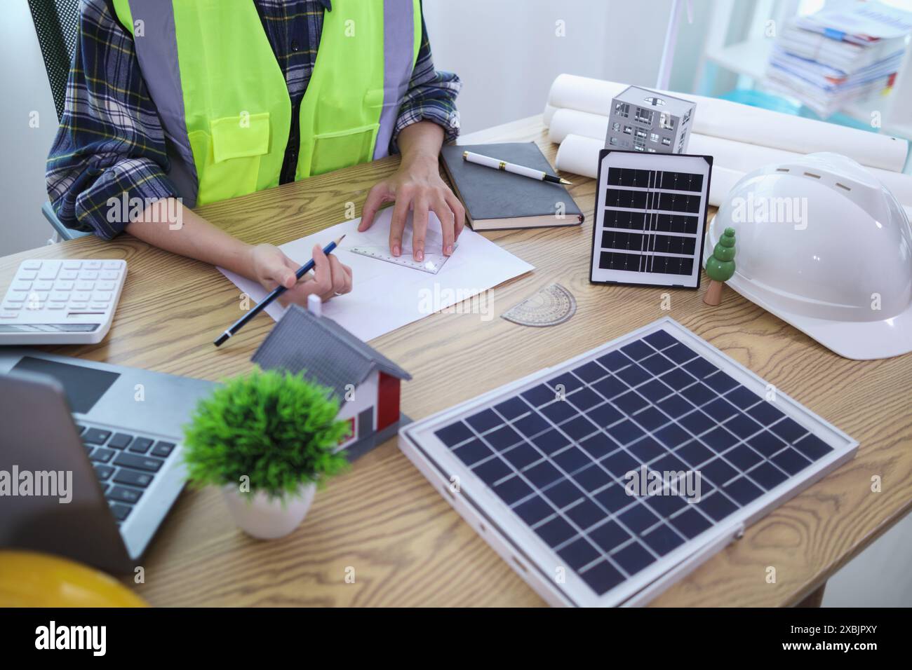 Les ingénieurs examinent les plans des architectes pour préparer l’installation de panneaux solaires et d’éoliennes sur le bâtiment afin de produire efficacement de l’électricité Banque D'Images