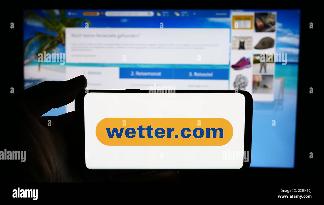 Personne tenant le téléphone portable avec le logo de la société allemande de portail météo wetter.com GmbH en face de la page Web de l'entreprise. Concentrez-vous sur l'affichage du téléphone. Banque D'Images