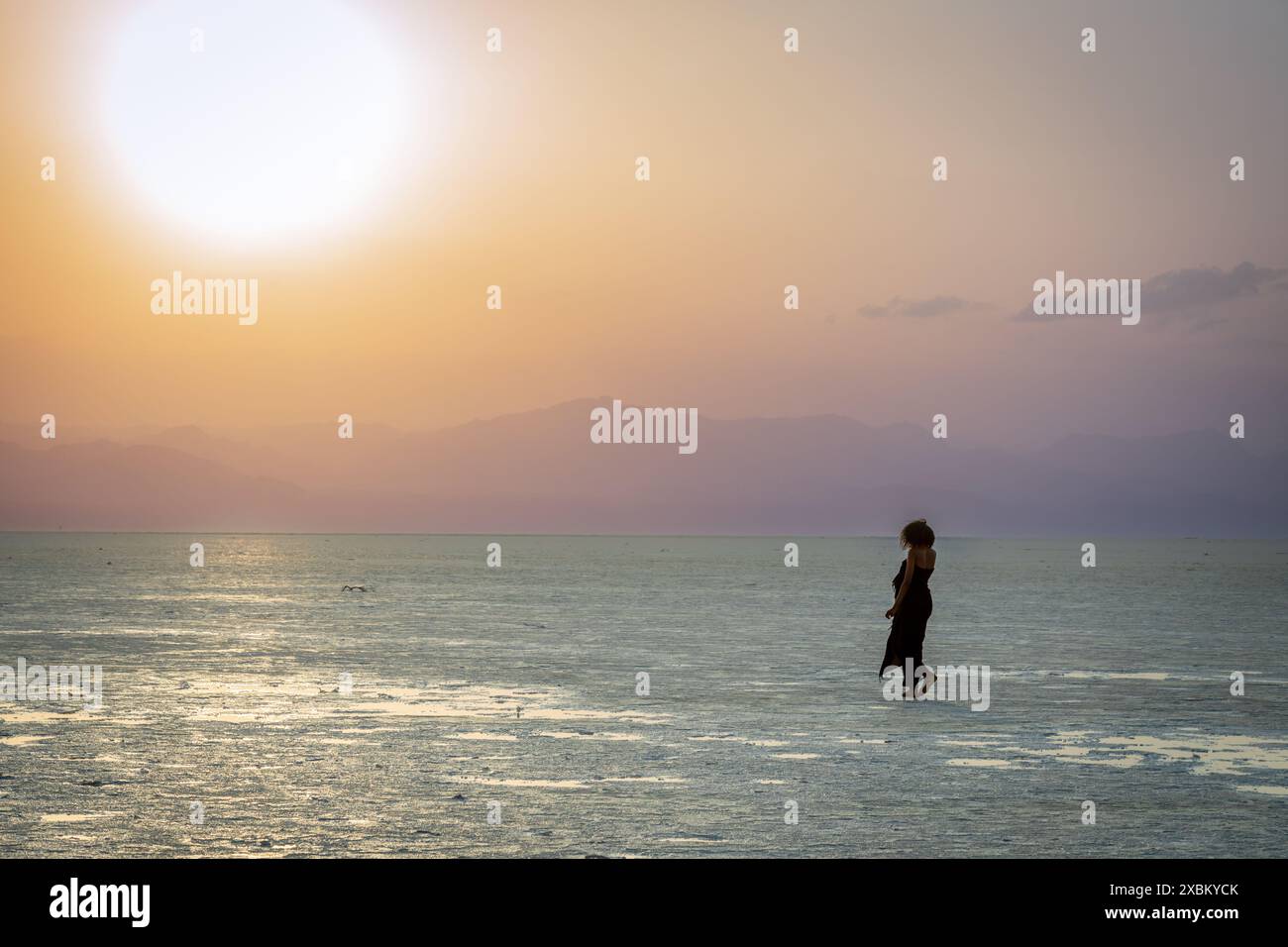 Les femmes figurent dans un coucher de soleil sur la surface du lac de sel blanc Karum, désert de dépression Danakil, région d'Afar, Ethiopie Banque D'Images