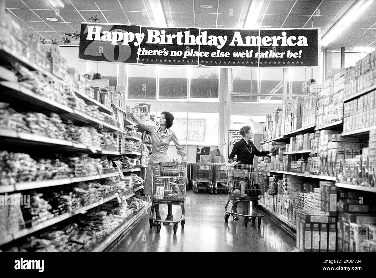 Deux femmes magasinant dans une épicerie sous la bannière suivante : «Joyeux anniversaire Amérique, il n'y a pas d'autre endroit où nous préférerions être!» Commémoration du bicentenaire des États-Unis, Marion S. Trikosko, U.S. News & World Report Magazine Photograph Collection, mai 1976 Banque D'Images