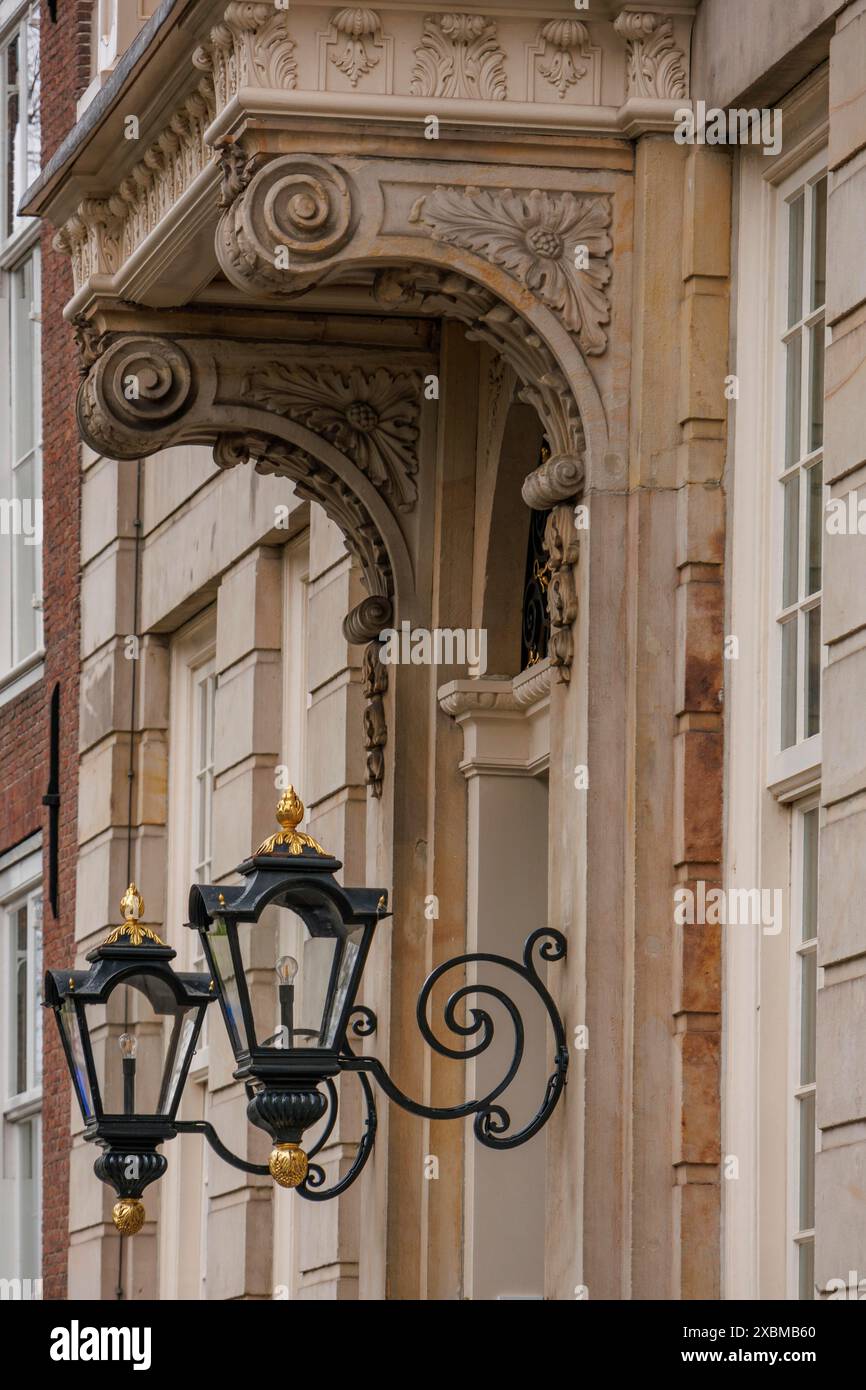 Vue détaillée d'un ornement de façade historique avec des ornements décoratifs en pierre et deux lanternes noires, la Haye, pays-Bas Banque D'Images