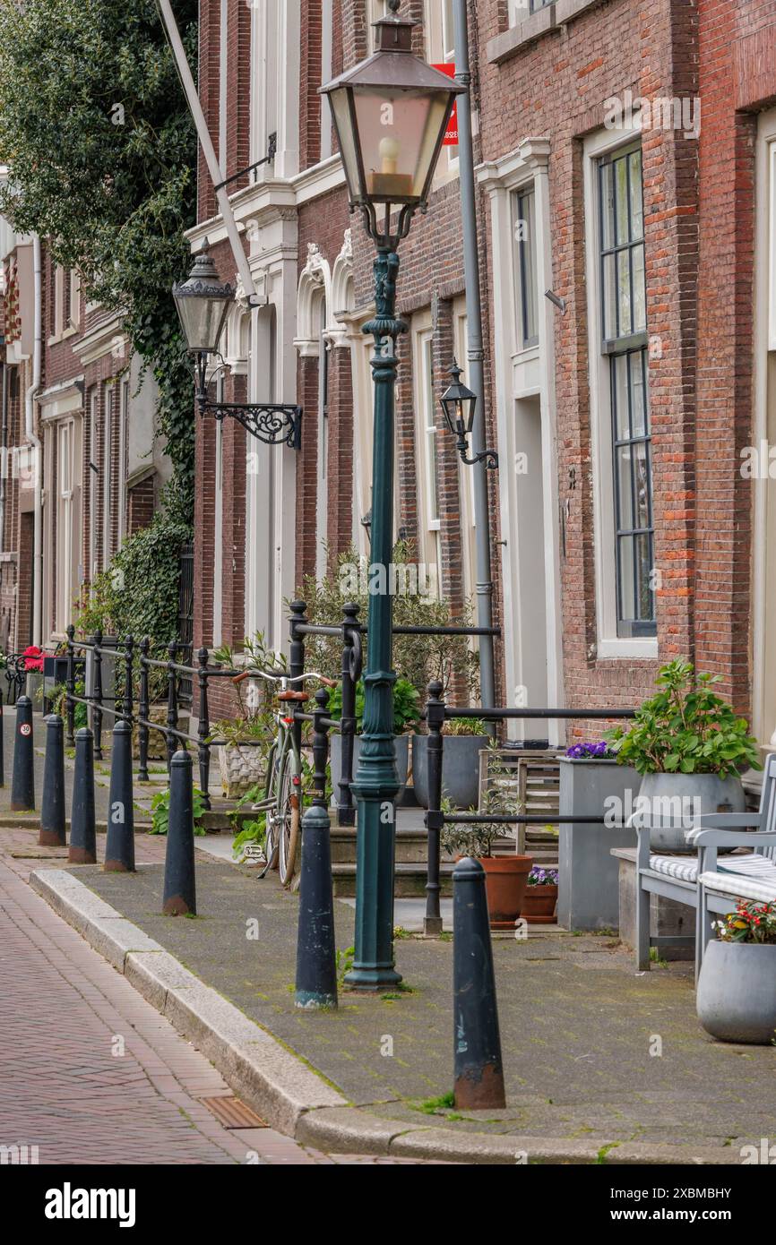 Vieille rue de la ville avec des lanternes classiques et des vélos devant des bâtiments en briques soignés, Dordrecht, hollande, pays-bas Banque D'Images