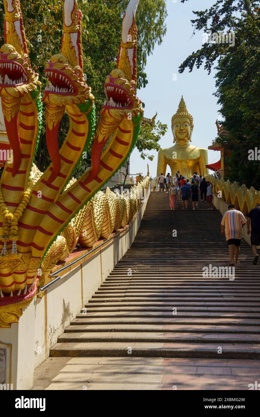 Statue de Bouddha doré en haut d'un large escalier, flanquée de figures de dragon doré, Pattaya, Thaïlande Banque D'Images