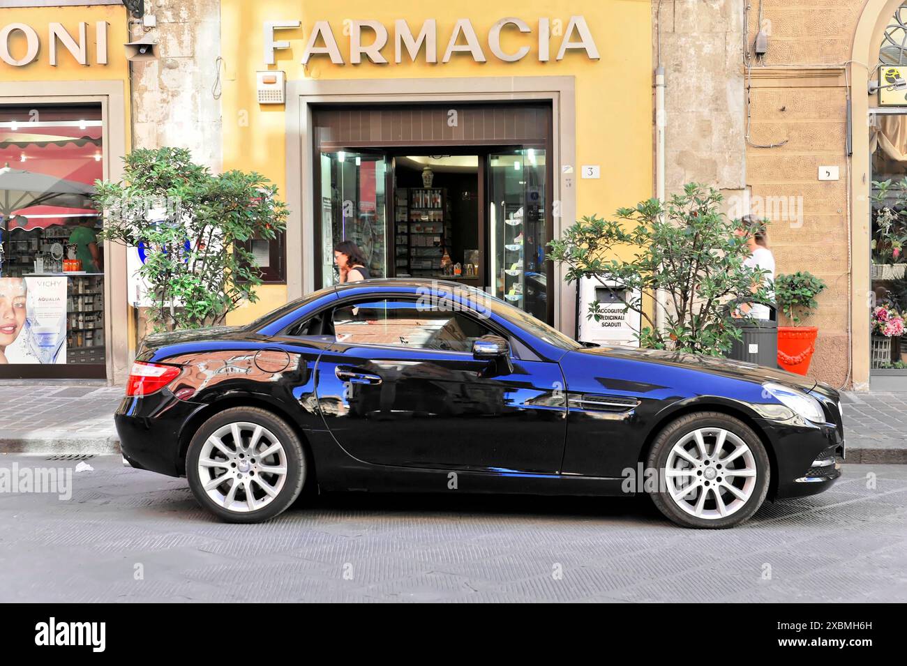 Pise, Toscane, Italie, Europe, Une voiture noire brillante est garée dans la rue devant une pharmacie Banque D'Images