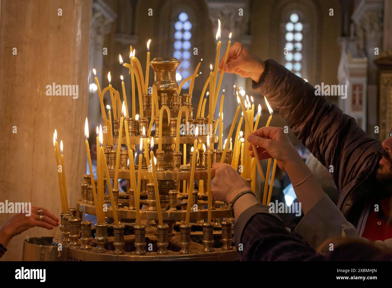 Plusieurs mains ont mis des bougies allumées dans un chandelier, Cathédrale orthodoxe grecque de l'Annonciation, Mitropolis, Athènes, Grèce Banque D'Images