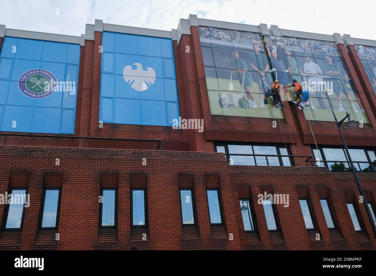 Les travailleurs collent la publicité pour Barclays Bank avant le tournoi de tennis de Wimbledon. Banque D'Images
