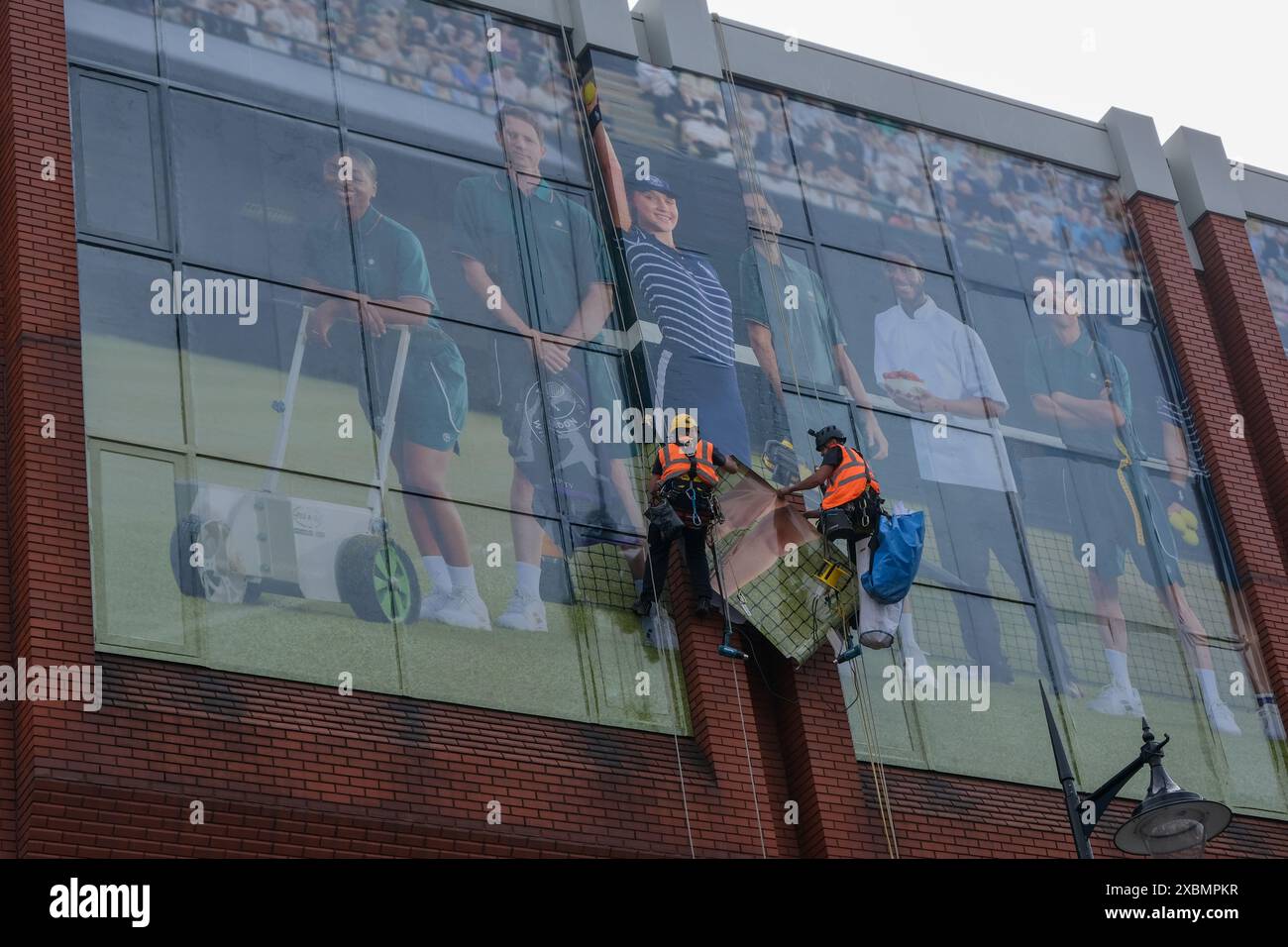 Les travailleurs collent la publicité pour Barclays Bank avant le tournoi de tennis de Wimbledon. Banque D'Images