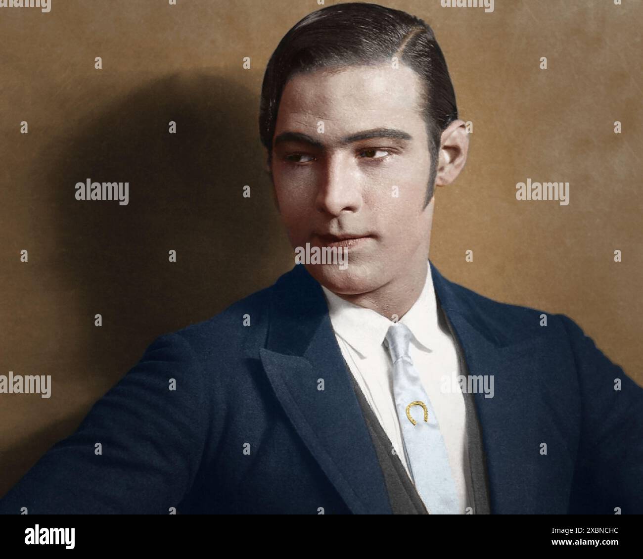 Une photographie vintage représentant un homme dans un costume intemporel avec des cheveux tranchants, mettant en valeur l'élégance classique et le style sophistiqué typique de la mode du début du XXe siècle. Portrait en studio de Rudolph Valentino, né sous le nom de Rodolfo Pietro Filiberto Raffaello Guglielmi di Valentina d’Antonguella le 6 mai 1895 à Castellaneta, en Italie. Il était une figure emblématique de l'ère du cinéma muet. Connu sous le nom de « Grand amant », il mourut le 23 août 1926. Sa mort prématurée d'une péritonite à l'âge de 31 ans provoque une hystérie de masse parmi ses fans, cimentant sa place dans l'histoire cinématographique. Il était également connu comme le « latin Lover » Banque D'Images