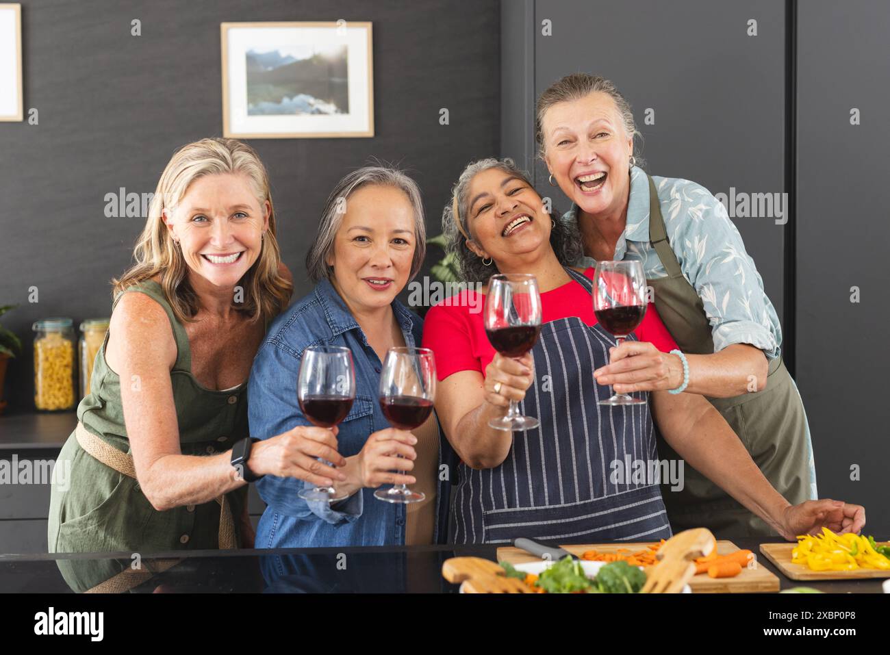 Groupe diversifié de femmes matures appréciant le vin et préparant la nourriture ensemble dans la cuisine Banque D'Images