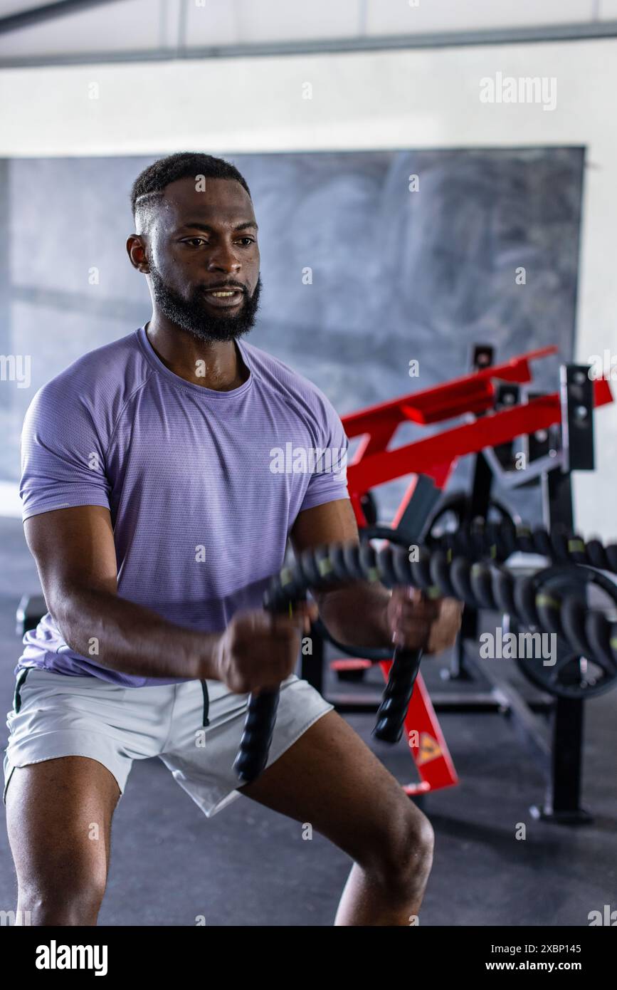 Exercice et entraînement, homme afro-américain utilisant des cordes de combat dans le gymnase Banque D'Images