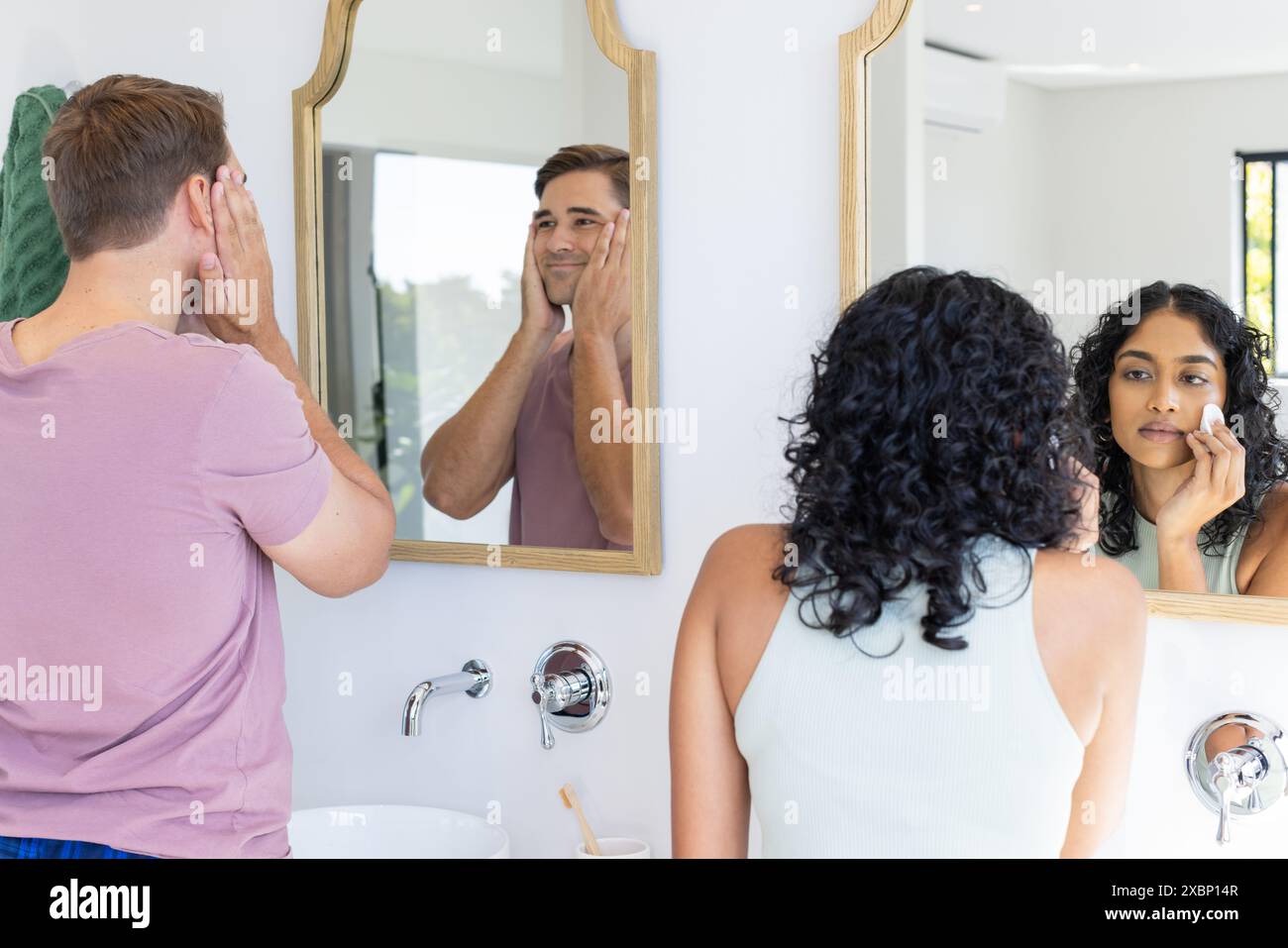 Couple diversifié se préparant devant les miroirs de salle de bains Banque D'Images