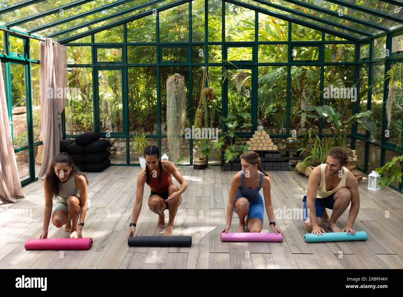 Diverses personnes à la classe de yoga déploient des tapis dans un studio vitré, espace de copie Banque D'Images