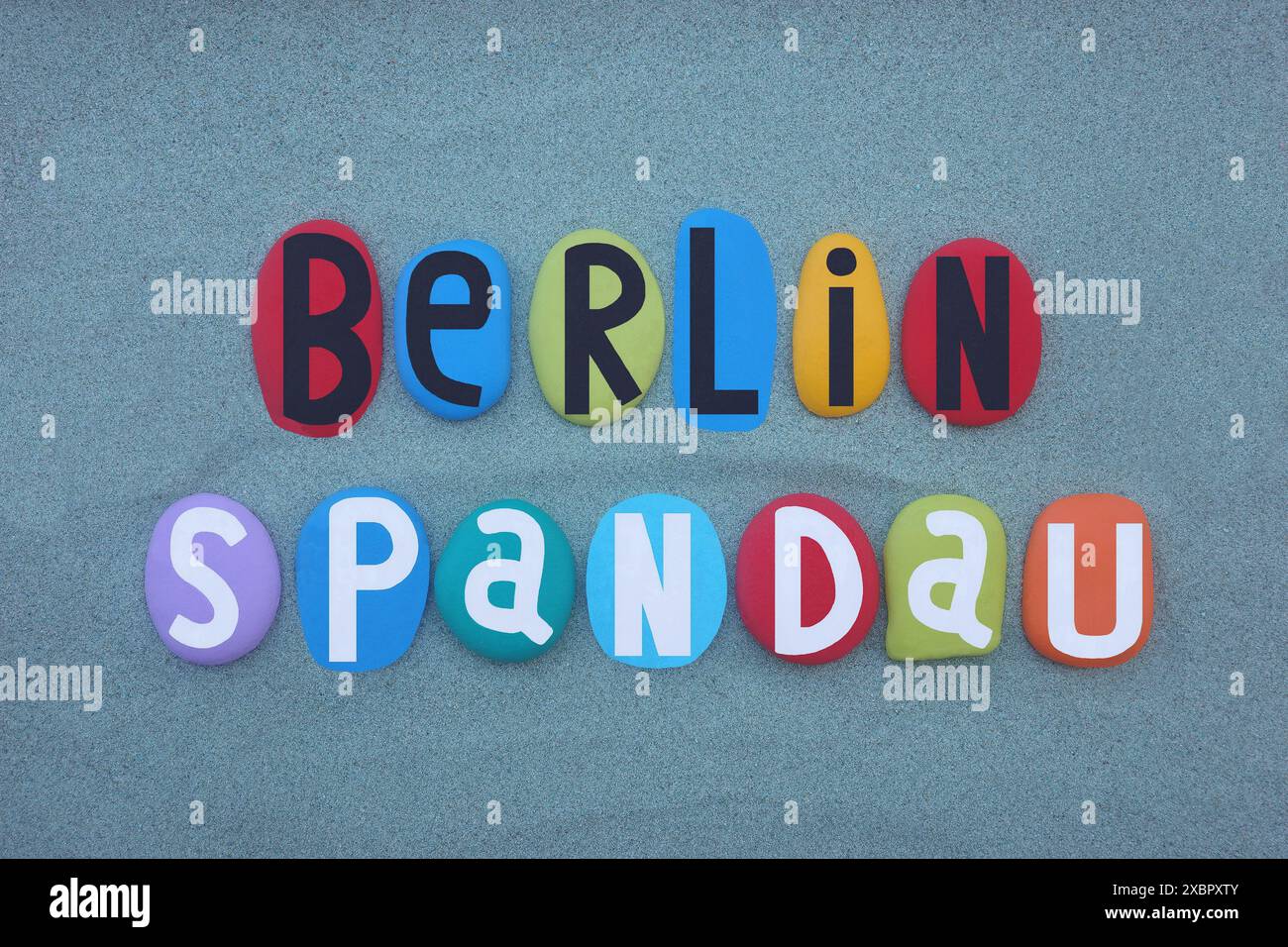 Quartier de Berlin Spandau, souvenir composé de lettres en pierre multicolores peintes à la main sur sable vert Banque D'Images