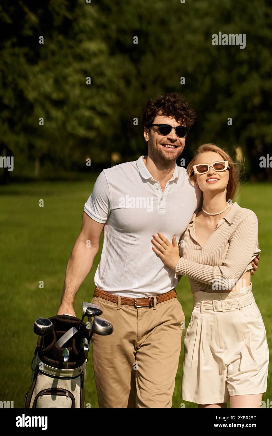 Un jeune homme et une jeune femme prennent une pose élégante dans un parc luxuriant, profitant d'une journée dans une tenue élégante. Banque D'Images
