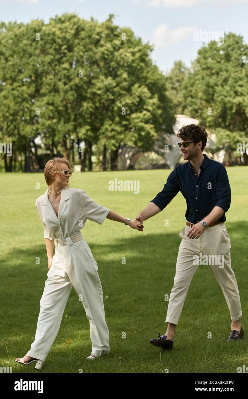 Un couple élégant se tient la main dans un parc luxuriant, entouré de verdure, incarnant l'élégance et la tranquillité. Banque D'Images