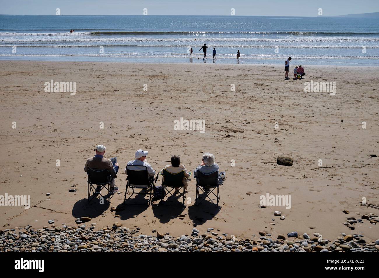 Quatre retraités se sont assis dans une rangée sur la plage au large du Cobble Landing à Filey, North Yorkshire East Coast, au nord de l'Angleterre, au Royaume-Uni Banque D'Images