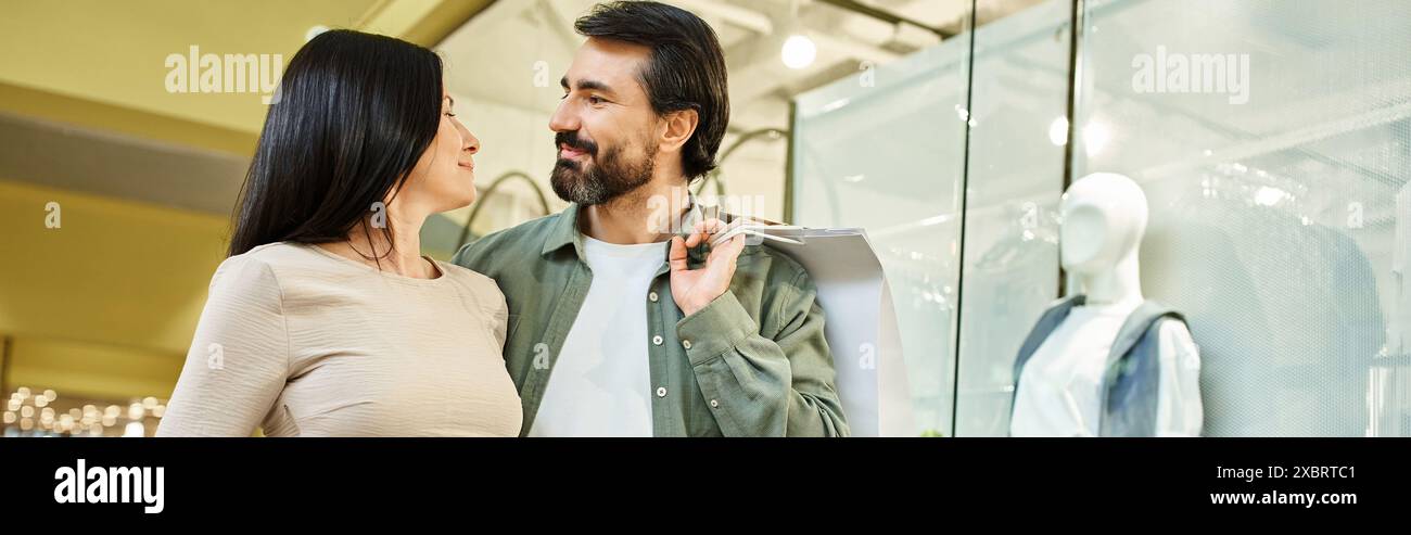 Un homme et une femme partagent un moment tendre alors qu'ils verrouillent les yeux dans un centre commercial animé. Banque D'Images