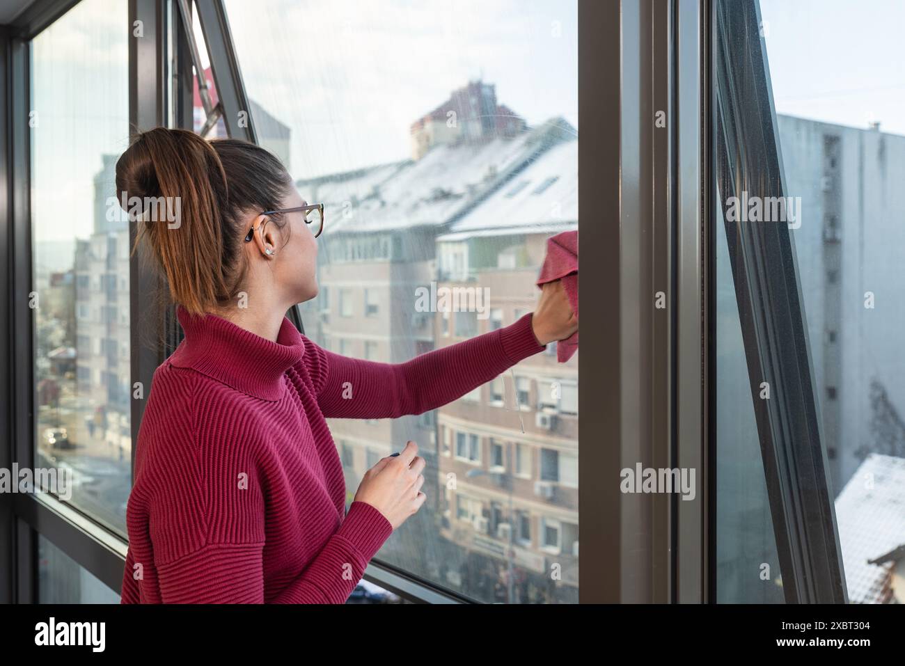 Temps de nettoyage. Jeune femme lavant et frottant le verre de fenêtre de la poussière et de la saleté avec un tapis, pour être propre et impeccable. Trouble obsessionnel compulsif. Banque D'Images