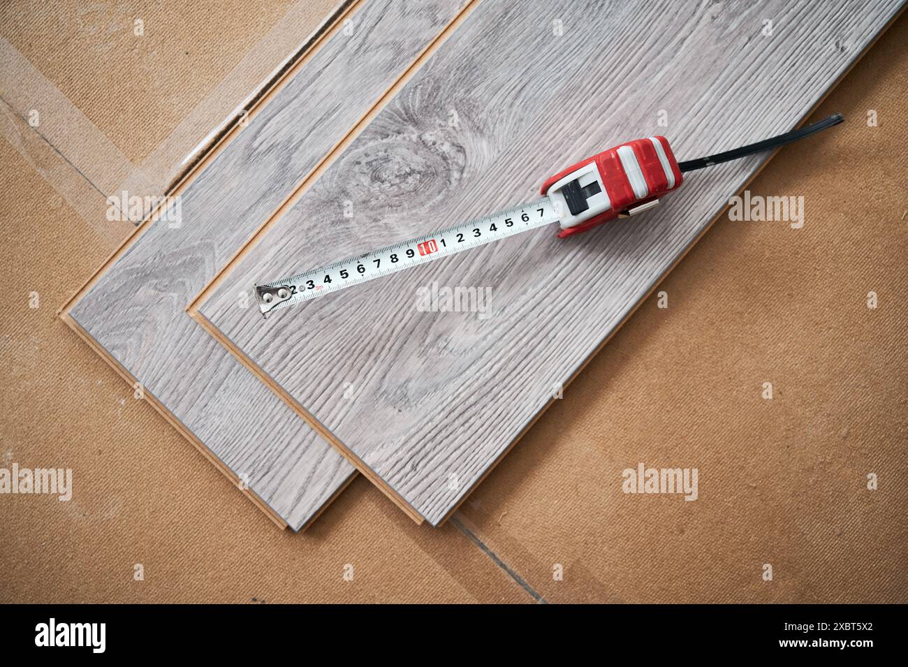 Vue de dessus du ruban à mesurer sur des planches de plancher en bois pour la rénovation de la maison et les travaux de construction. Ruban à mesurer métallique sur des échantillons de panneaux stratifiés avec motif et texture en bois pour les revêtements de sol. Banque D'Images
